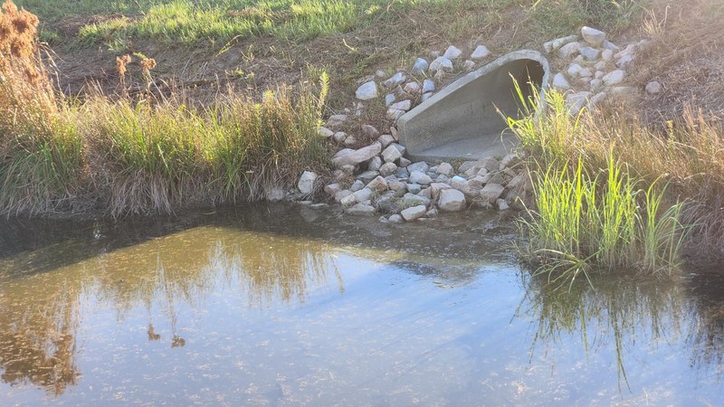 Stormwater outfall &mdash; reinforced concrete pipe, riprap apron and receiving pond after seasonal rain